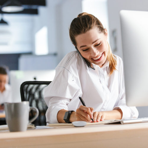 Cheerful young businesswoman sitting at her workplace